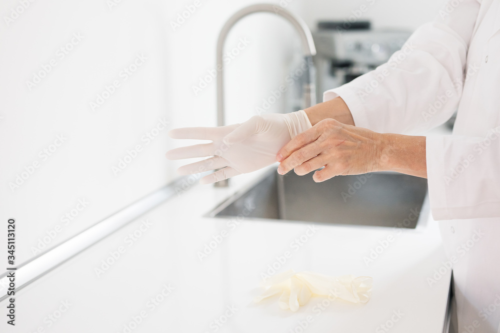 Frau wäscht Hände mit Handschuhen
