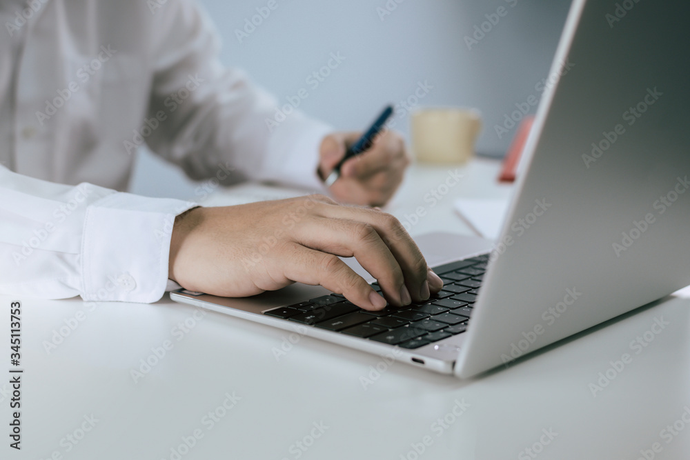 businessman in white shirt hand working on digital laptop and writing about finance with document report on desk at home office, work from home, digital online marketing and financial business concept businessman in white shirt hand working on digital laptop and writing about finance with document report on desk at home office, work from home, digital online marketing and financial business concept