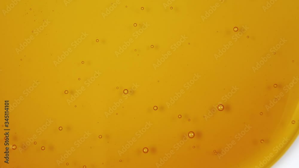 Honey flows down a white background. Abstract colorful background with small bubbles close up. Uniform slow motion. Macro shot Honey flows down a white background. Abstract colorful background with small bubbles close up. Uniform slow motion. Macro shot