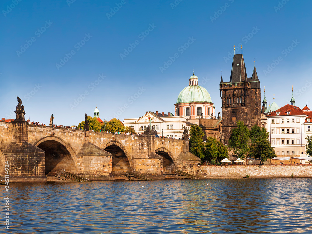 View of the Charles bridge over the Vltava river, the bridge tower and the church of St. Francis of Assisi in Prague. Czech Republic