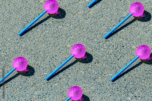 A thrown pink lollipop on a dirty road melting under the rays of the hot summer sun.