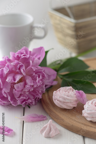 Pink marshmallow and pink peony on a white wooden table