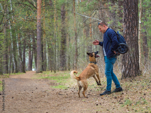 A man is playing in the forest with his dog.