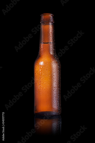 Brown small bottle full of liquid with drops on it on a black background