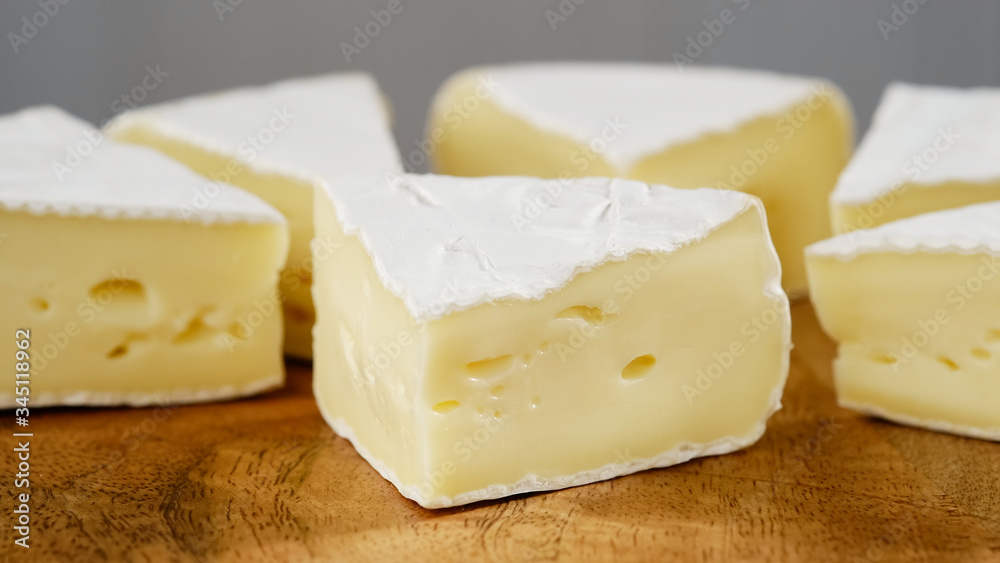 pieces of soft cheese Camembert on light grey background. Delicious pieces of white mold cheeses with soft textures Camembert close up, macro