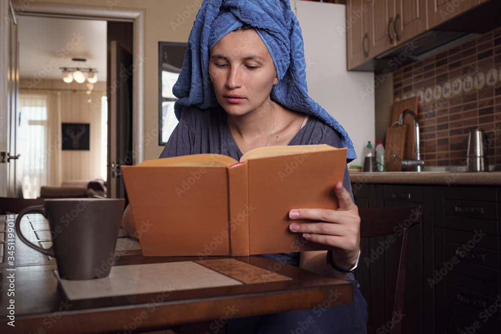 Young asian woman reads a book in the kitchen. Young asian woman reads a book in the kitchen.