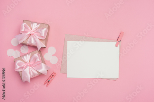 Gift boxes with pink ribbon bow and blank postcard on pastel pink background. Banner mock up for Women's day, Birthday or Mothers Day. Best gift for women concept. Top view, flat lay with free space. 