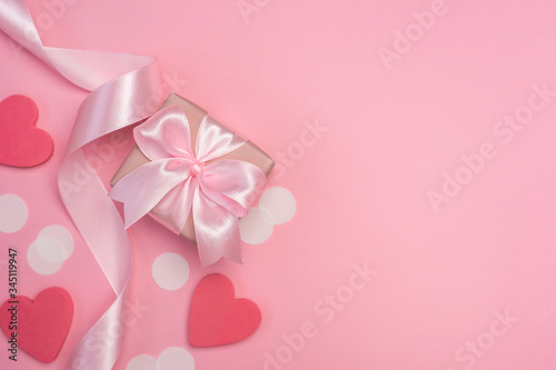 Gift box with pink ribbon bow on pastel pink background with white confetti and hearts. Banner for Valentines day, Birthday or Mothers Day. Best gift for women concept. Top view, flat lay free space.  © kaloriya