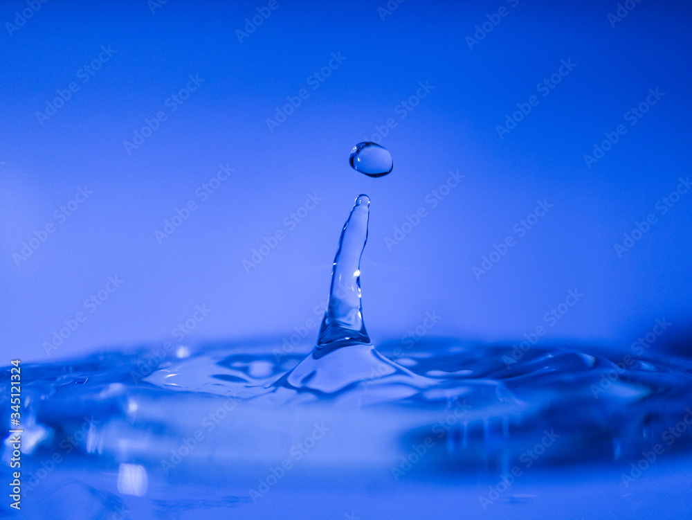 Water drop creating waves ripples and air borne water droplet Water drop creating waves ripples and air borne water droplet