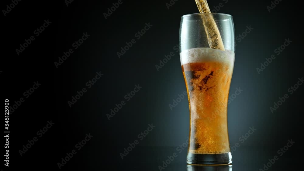 Super Slow Motion Shot of Pouring Fresh Beer into Glass on Black Background at 1000fps.