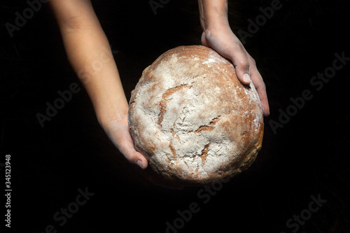 Hands holding fresh round bread.