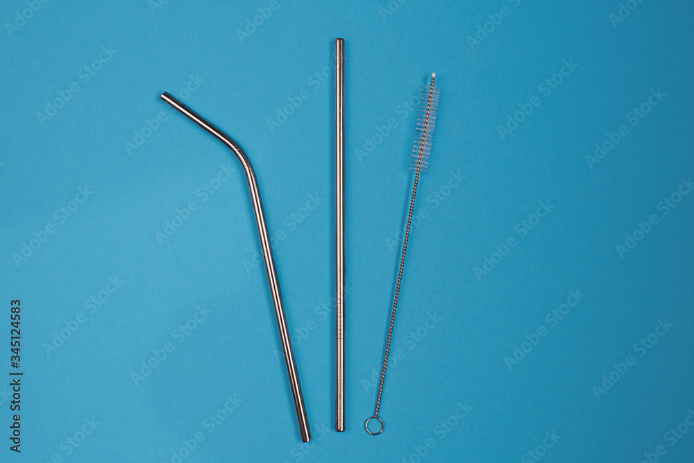 Eco reusable stainless steel straws for drinks and cocktails and cleaning brush on blue background. Eco reusable stainless steel straws for drinks and cocktails and cleaning brush on blue background.