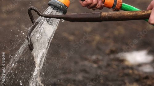 Professional worker washes glander with special washing tool, specialist cleaning instrument after working in garden, wash gardens after making holesfor seedings in ground. Agriculture working. photo