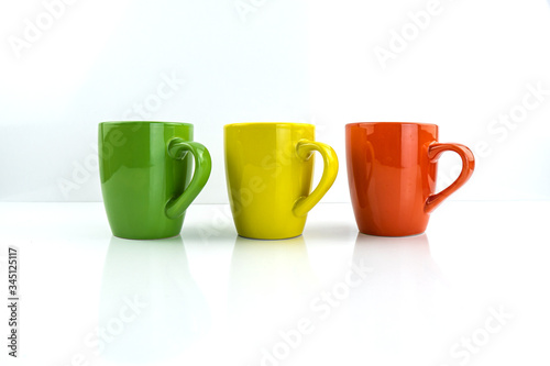 Porcelain cups of different colors stand on a white background.