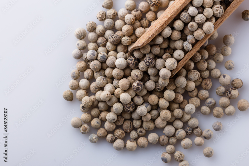 white peppercorns in wooden scoop on white background white peppercorns in wooden scoop on white background