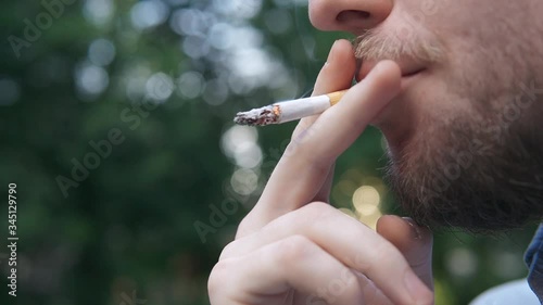 Bearded man smokes a cigarette on background evening lights city