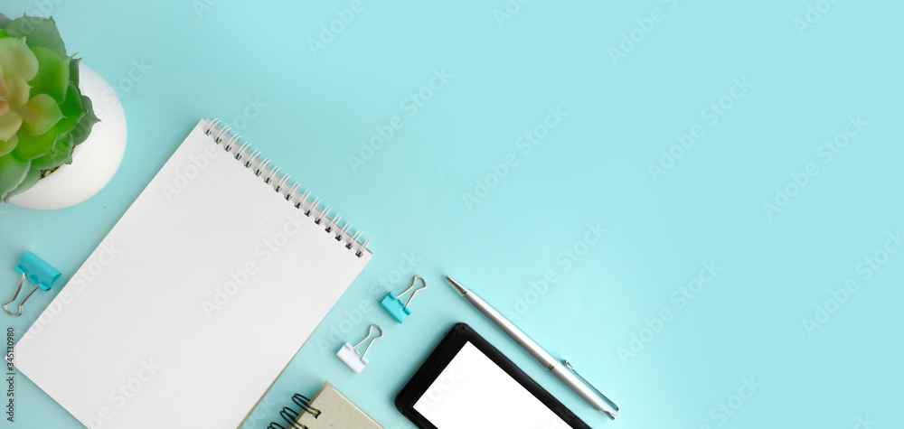 Minimalist workplace with empty notepad, smartphone, succulent and stationery on mint background. Online education or business concept. Banner / header with copy space Minimalist workplace with empty notepad, smartphone, succulent and stationery on mint background. Online education or business concept. Banner / header with copy space