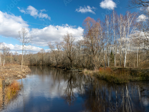 river view from the bridge, small river in early spring, blue sky and reflections in the water