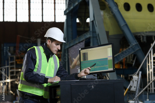 Portrait of a man , factory engineer in work clothes controlling the work process at the airplane manufacturer.