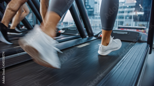 Athletic People Running on Treadmills, Doing Fitness Exercise. Strong Women and Men Training in the Modern Gym. Sports People Workout in Fitness Club. Ground Shot.