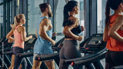 Athletic People Running on Treadmills, Doing Fitness Exercise. Athletic and Muscular Women and Men Actively Training in the Modern Gym. Sports People Workout. Back View Shot