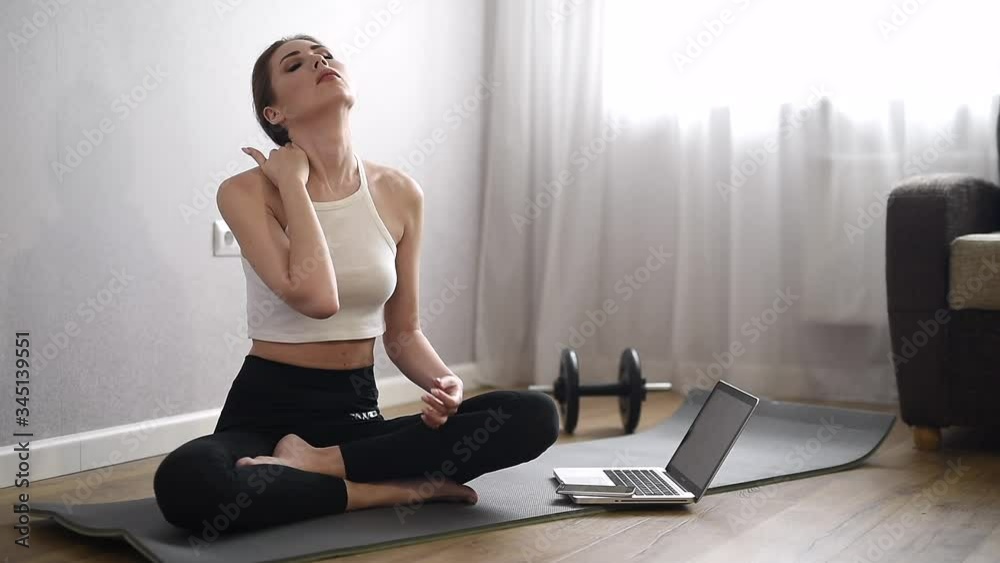 A young woman practicing meditation at home. Yoga time. Sports on self-isolation and quarantine. A girl is meditating while sitting in her apartment on the floor. A young woman practicing meditation at home. Yoga time. Sports on self-isolation and quarantine. A girl is meditating while sitting in her apartment on the floor.