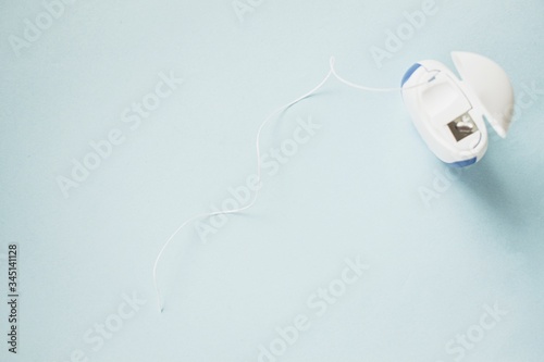Fotografie Dental floss on a blue background. Oral hygiene, teeth cleaning.