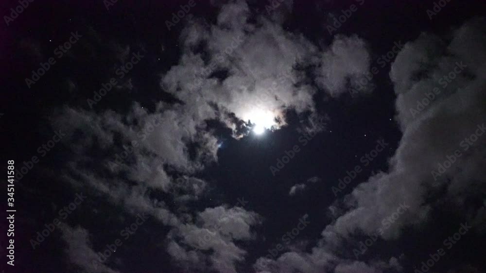 vidéo en temps réel de plusieurs satellites alignés et se déplaçant à égale distance en passant devant la lune qui est partiellement derrière les nuages