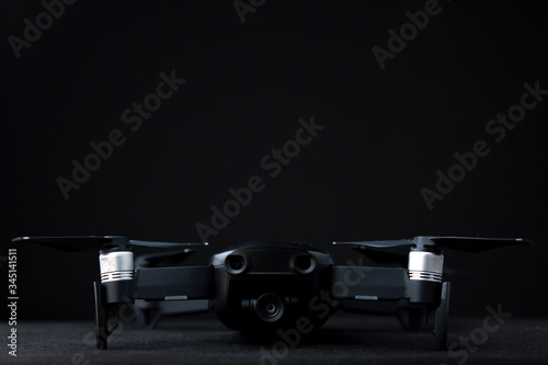 Quadcopter drone with props, gimbal and camera and front sensors studio low key still life against a dark grey background photo