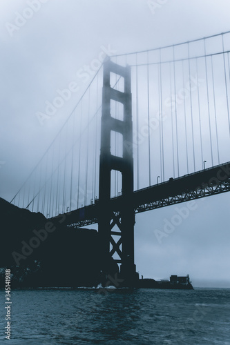 Moody photo of the Golden Gate Bridge from a Yacht. Foggy rainy day under the Golden Gate Bridge in San Francisco. Overcast weather and bad climate conditions.