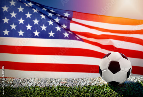 Soccer or football on green grass, on flag of United States of America background