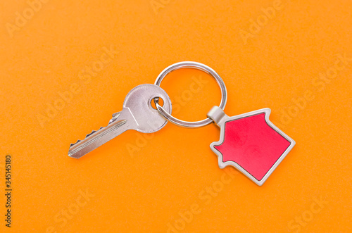 key chain with house symbol and keys on orange background,Real estate concept