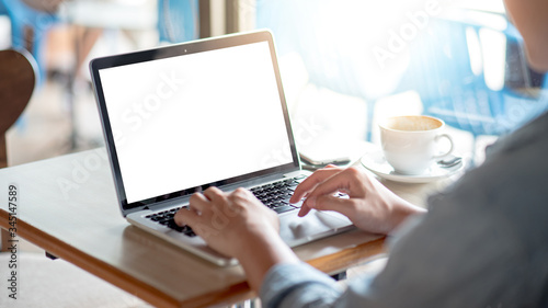 Asian freelance man using laptop computer working in the cafe. Businessman in casual clothing doing online conference or telecommuting. Remote work from anywhere. Blank monitor screen for advertising.