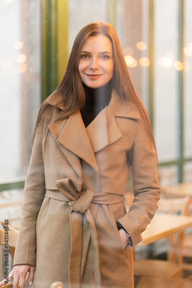 Outdoor fashion portrait of stylish young woman having fun, emotional face , laughing, Urban city street style wearing dark casual trousers, white sweater,creamy coat. and sunglasses Fashion concept.