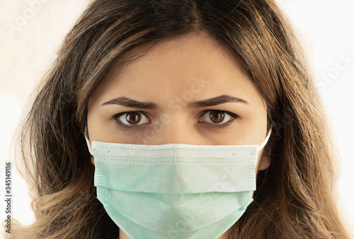 Studio portrait of young woman wearing a face mask  looking at camera  close up  isolated on white background