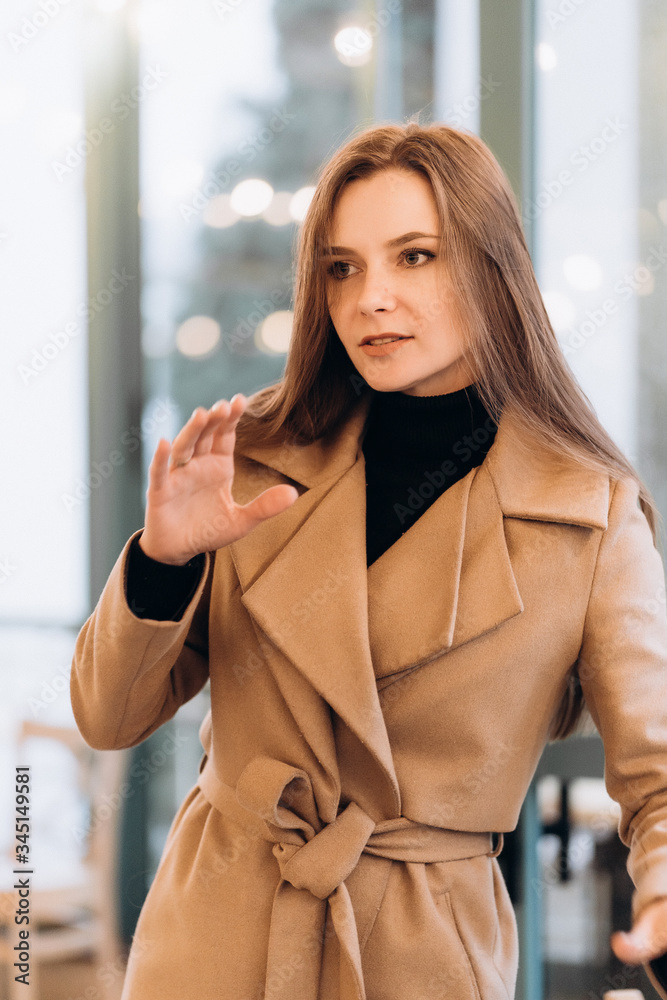Outdoor fashion portrait of stylish young woman having fun, emotional face , laughing, Urban city street style wearing dark casual trousers, white sweater,creamy coat. and sunglasses Fashion concept.