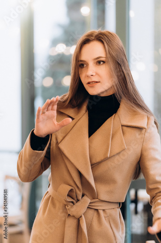 Obraz na płótnie Outdoor fashion portrait of stylish young woman having fun, emotional face , laughing, Urban city street style wearing dark casual trousers, white sweater,creamy coat. and sunglasses Fashion concept. w salonie