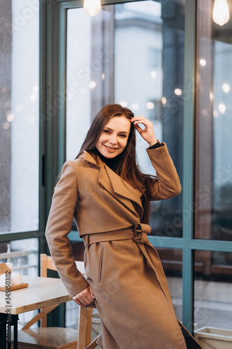 Obraz na płótnie Outdoor fashion portrait of stylish young woman having fun, emotional face , laughing, Urban city street style wearing dark casual trousers, white sweater,creamy coat. and sunglasses Fashion concept. w salonie
