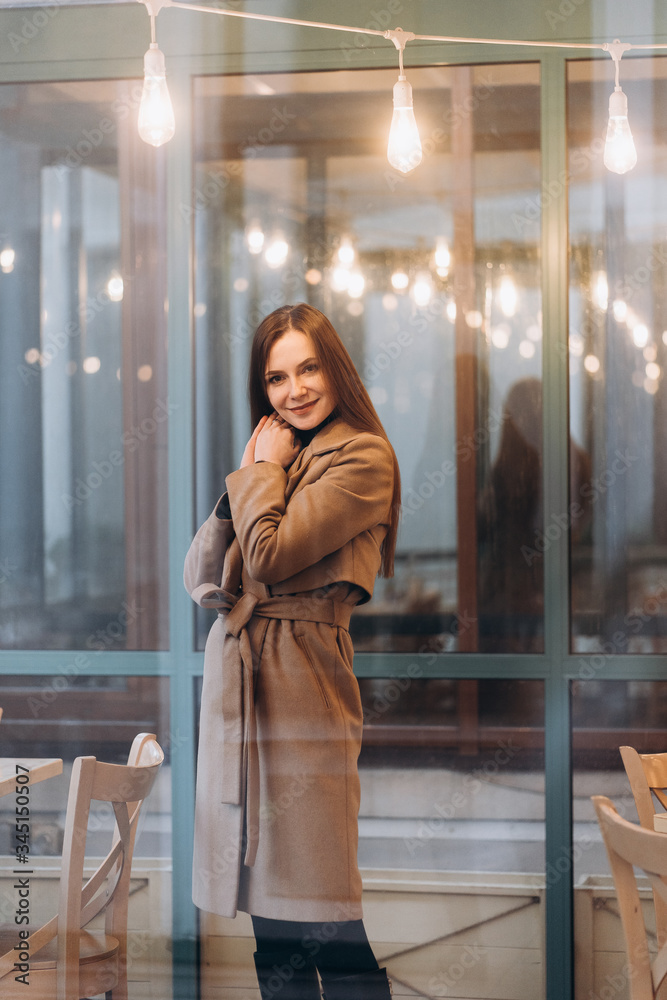 Outdoor fashion portrait of stylish young woman having fun, emotional face , laughing, Urban city street style wearing dark casual trousers, white sweater,creamy coat. and sunglasses Fashion concept.