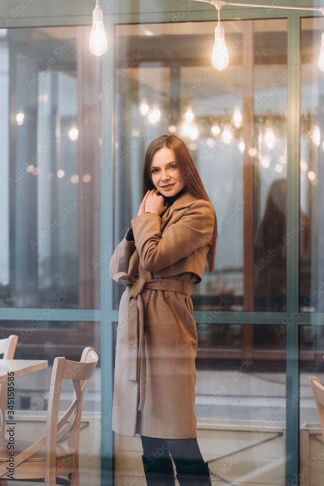 Outdoor fashion portrait of stylish young woman having fun, emotional face , laughing, Urban city street style wearing dark casual trousers, white sweater,creamy coat. and sunglasses Fashion concept.
