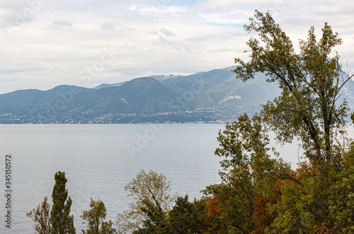 Nature, mountains in the clouds and settlements around Lake Garda near the Sirmione town in Lombardy, northern Italy