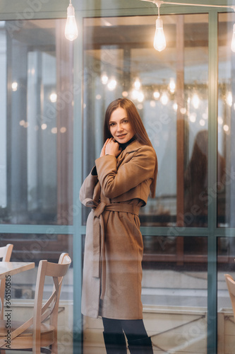 Obraz na płótnie Outdoor fashion portrait of stylish young woman having fun, emotional face , laughing, Urban city street style wearing dark casual trousers, white sweater,creamy coat. and sunglasses Fashion concept. w salonie