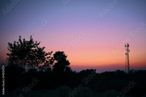 silhouette image of a blue and reddish sky during sunset with tress in the foreground