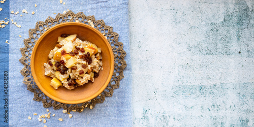 Oatmeal granola fruit porridge with banana, apples and raisins. Healthy sweet vegan breakfast. 