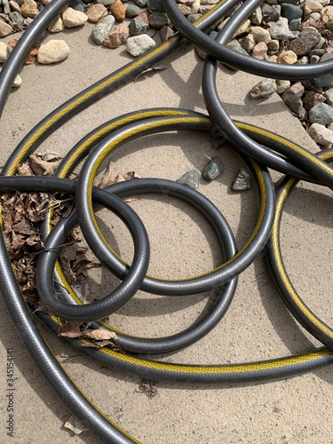 kinked, twisted, and knotted black garden hose on rock photo