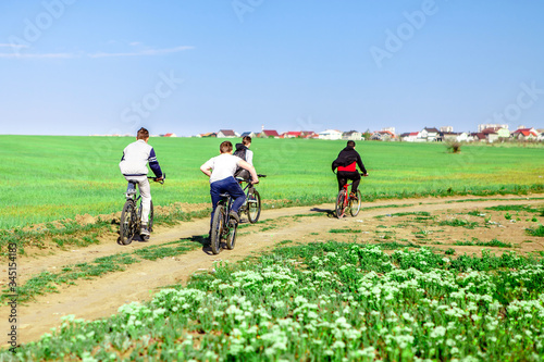 four boys riding bicycles along a field