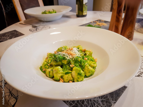 gnocchi with pesto on white plate with cheese