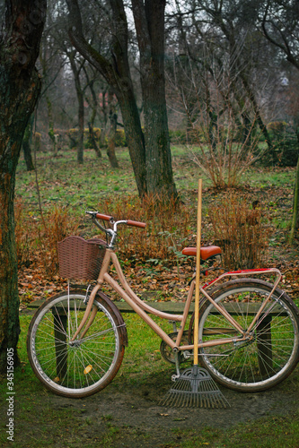 Old bike and brooms. Retro styled image with a bicycle and garden tools photo