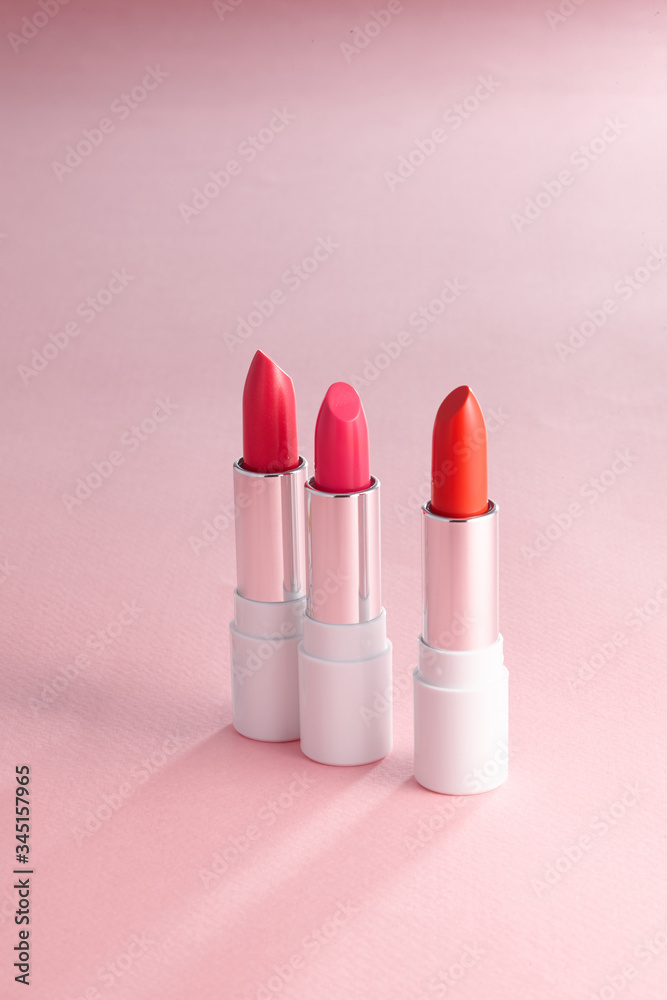Three red lipstick with a pink background. Three red lipstick with a pink background.