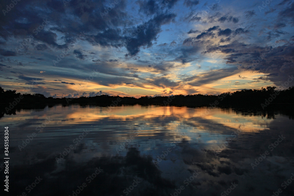 Colorful sunset and reflection on Nine Mile Pond after storm in Everglades National Park, Florida.